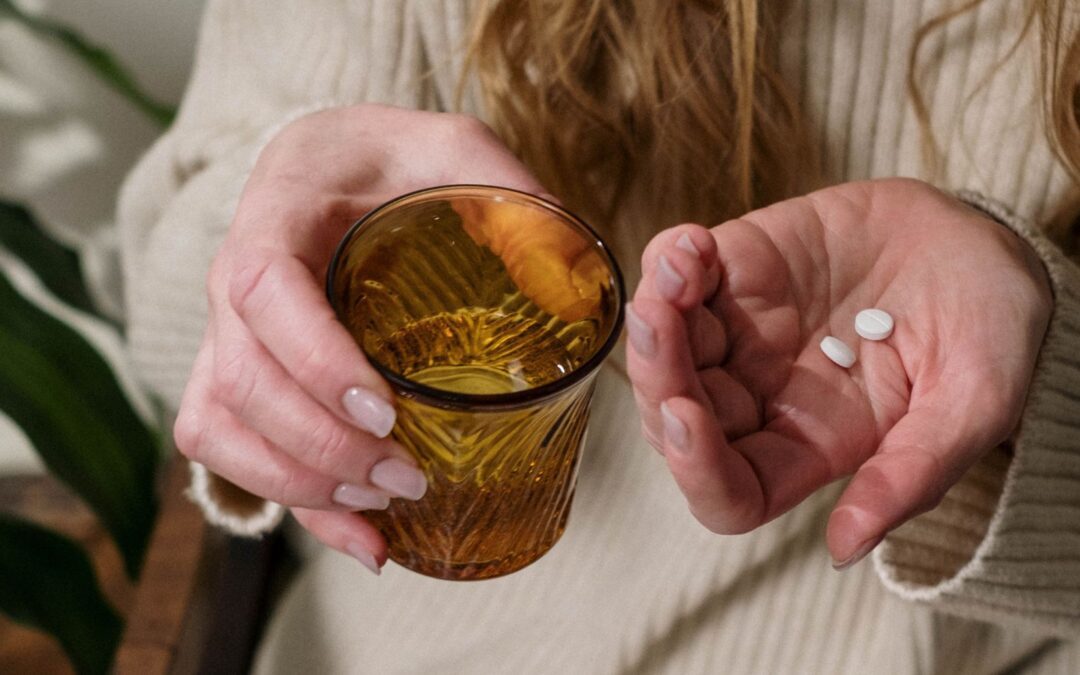 woman holding a glass of water and abortion pills
